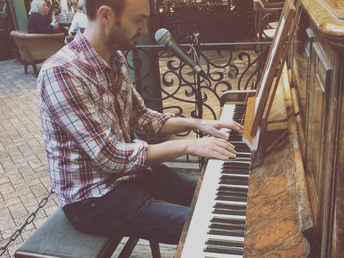 Phil Richardson singing and playing an upright piano in a bar