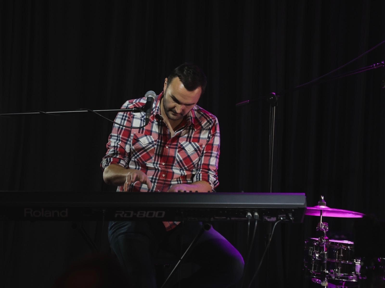 Phil Richardson playing keys on stage with a band