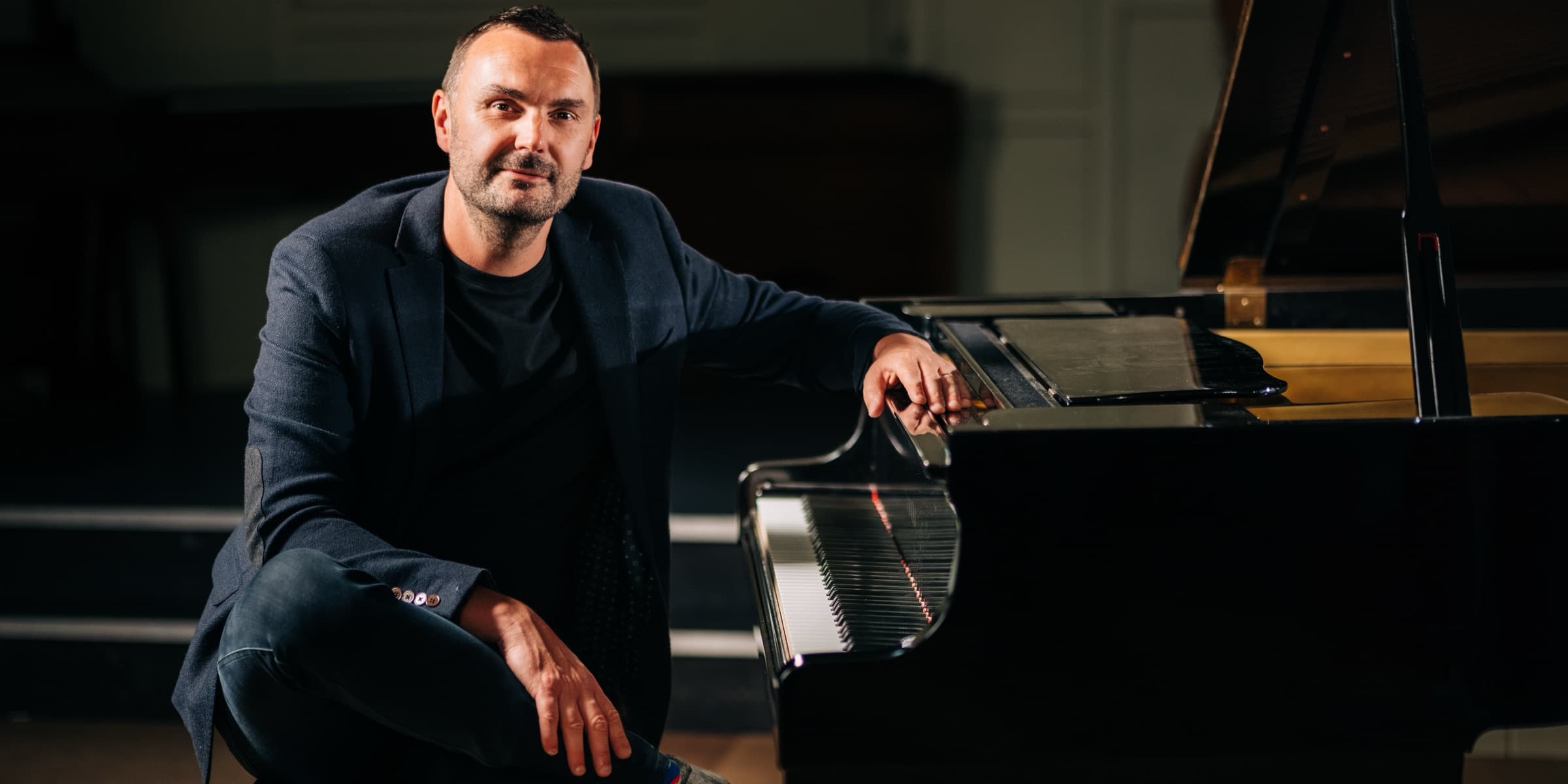 Phil Richardson seated beside a grand piano